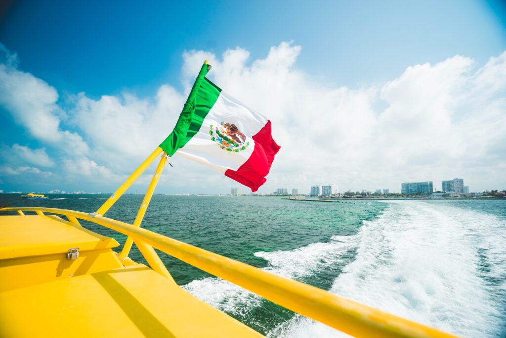 Mexican flag waving in the breeze off the back of the ferry to isla mujeres as it leaves Cancun.