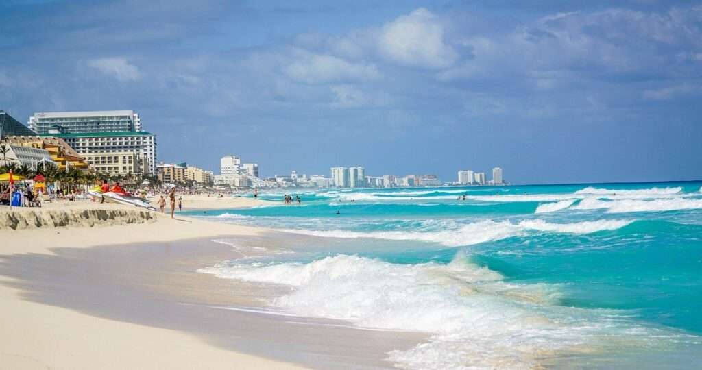 Northbound view of Playa Delfines in Cancun, with the beach on the left and the ocean waves on the right.