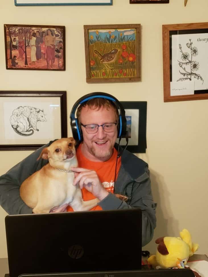 David holding a brown chihuahua while working online at his computer during one of our house sits.