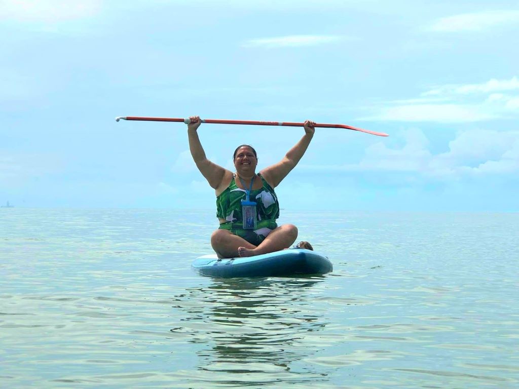 Brodi sitting on a paddleboard in the ocean.