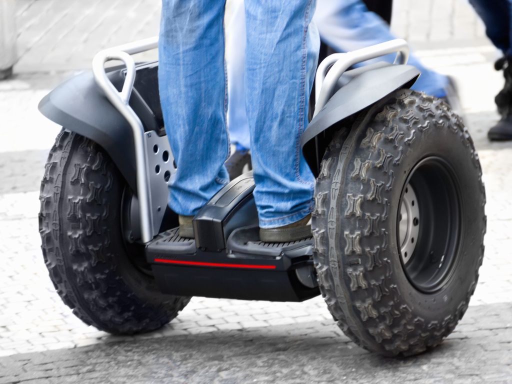 man standing on a segway, shown from the knees down