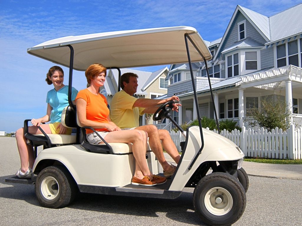family driving a golf cart past a house