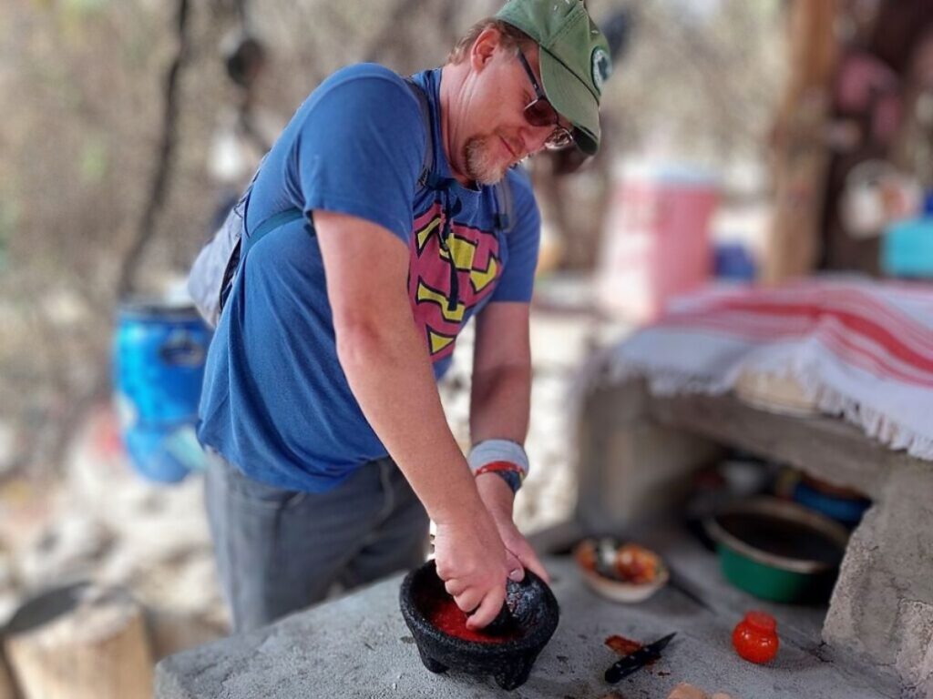 David making red salsa with a black mortar and pestle.