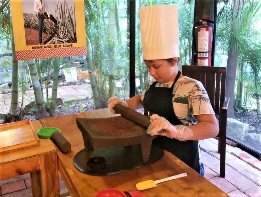 Little Man grinding cacao beans by hand