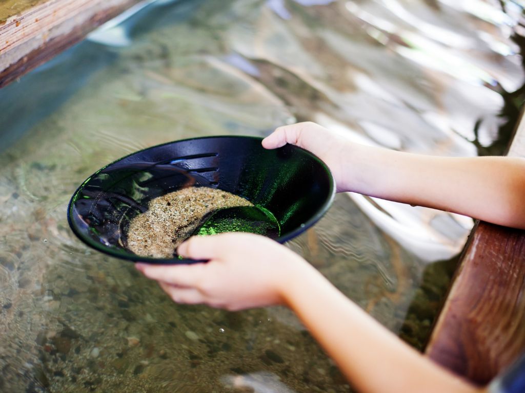 Kid panning for gold in a stream