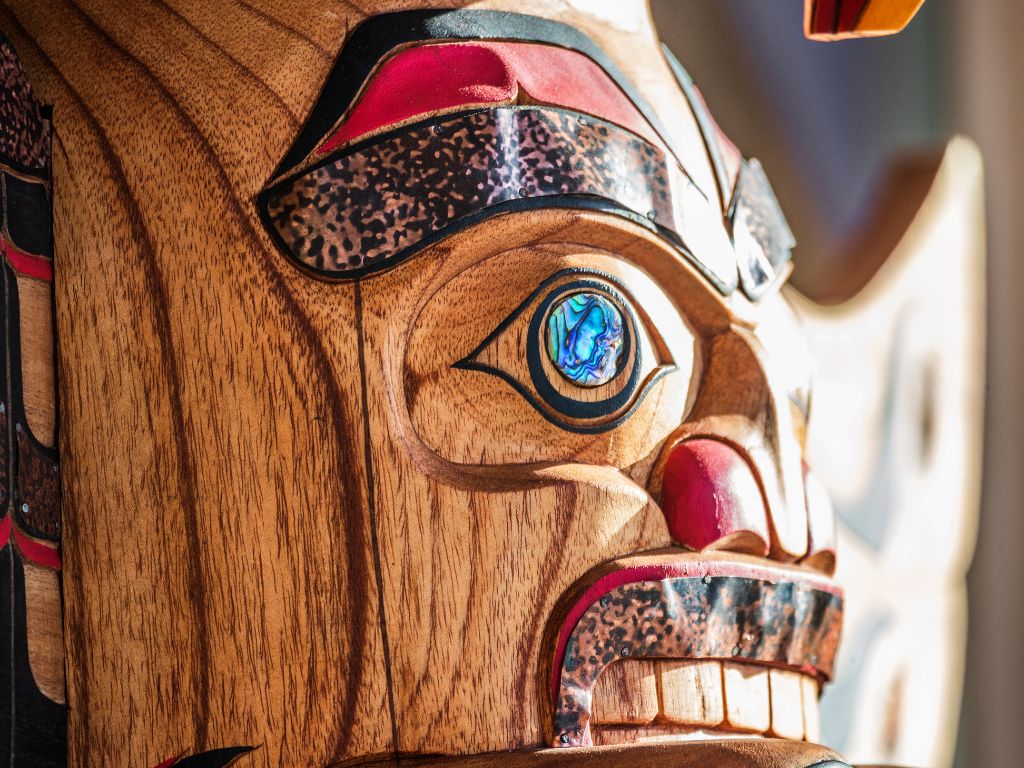 Close up of a wooden face on a totem pole