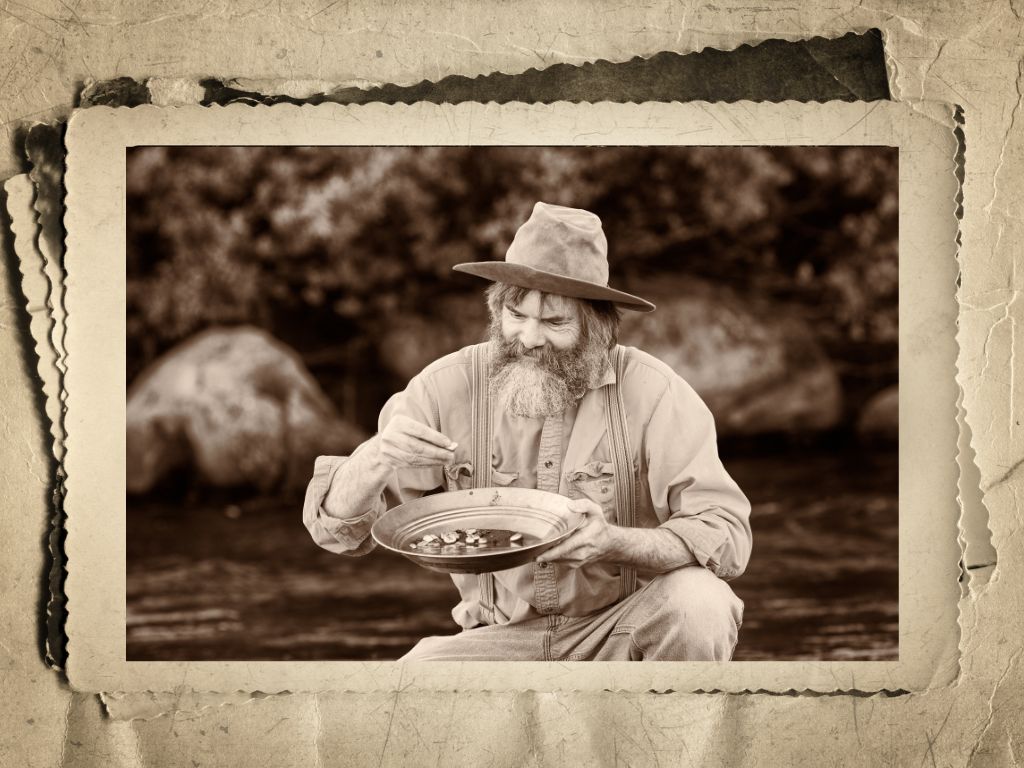 Old fashioned sepia photo of a man panning for gold in a river
