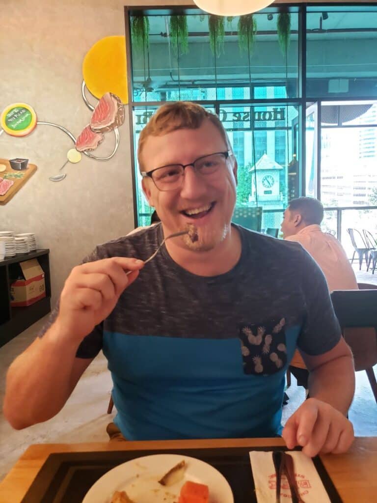 David smiling and taking a bite of steak at Bife Charcoal Steakhouse.