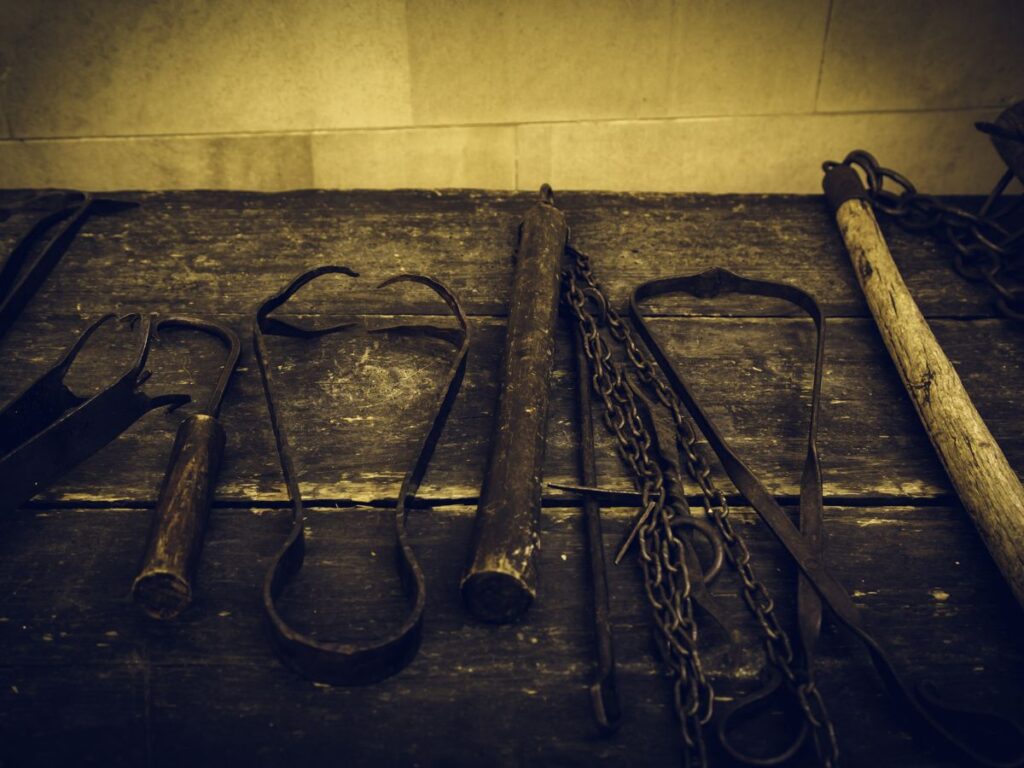 Medieval torture instruments lined up on a table. Photo is in sepia tones to make it look old.