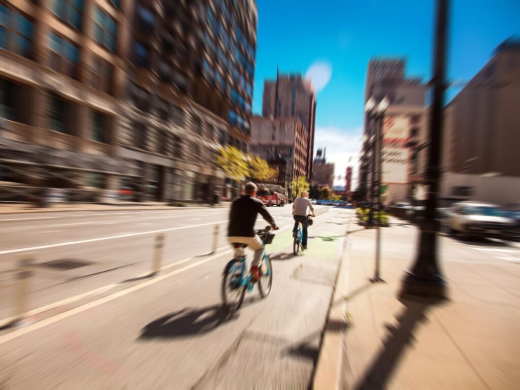 Two people riding bikes in a bike lane in Chicago. The background is blurred.