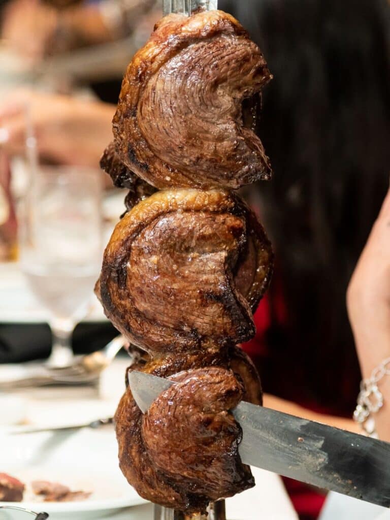 Close up of three full steaks on a skewer at a Brazilian-style steakhouse.