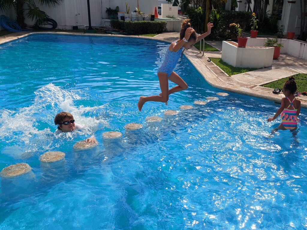 Little Man swimming with 2 kids in a swimming pool in Mexico