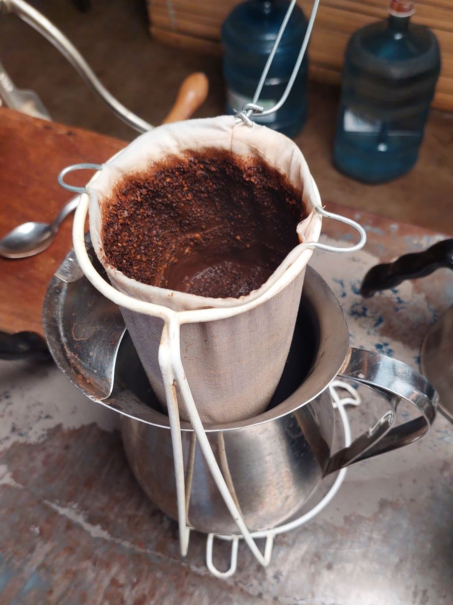 Cloth filtered coffee into a metal pitcher
