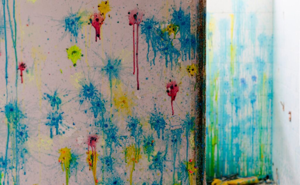 blue, yellow, and red paintballs exploded on a white wall