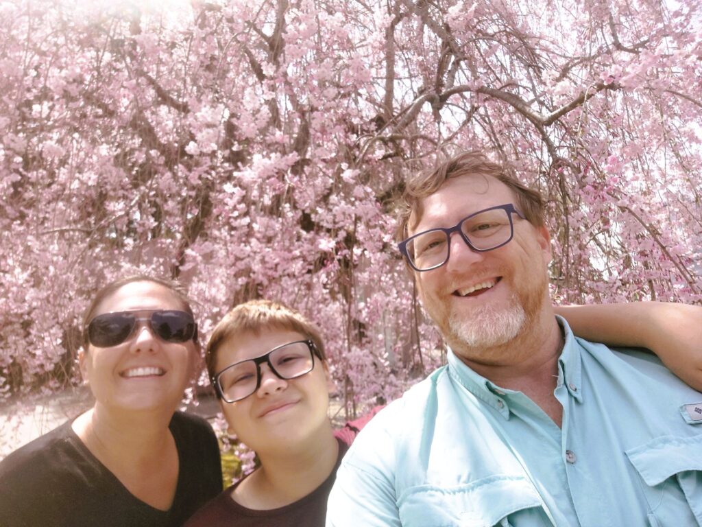 My family in front of a blossoming pink cherry blossom tree in Japan.